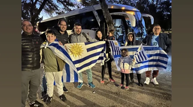 Viajeros con banderas uruguayas junto al bus