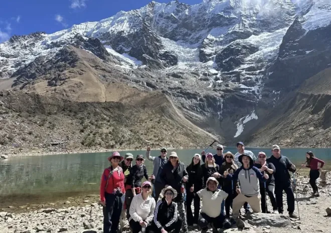 Grupo de viajeros junto a una laguna rodeada de montañas