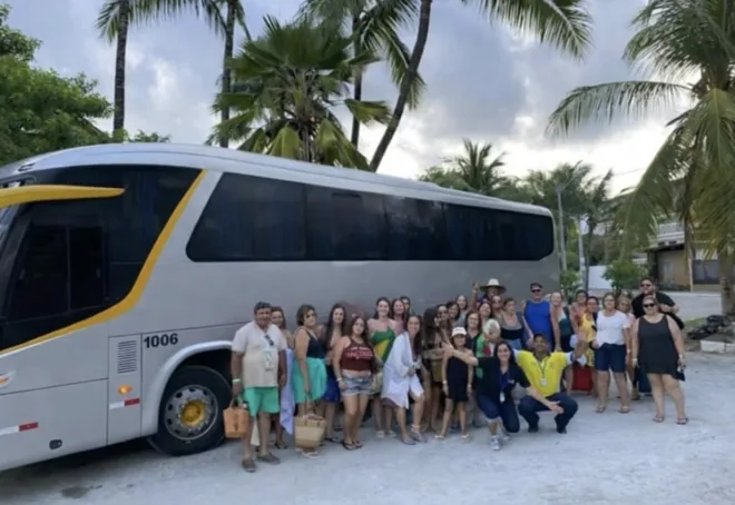 Viajeros junto a un bus entre palmeras